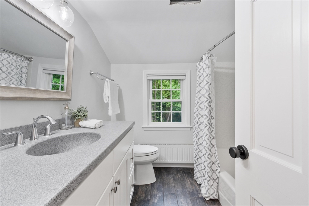 254 Taylor Road Stow, MA 01775 - Photo 27 of 42 a bathroom with a granite countertop sink a toilet a mirror a window and shower