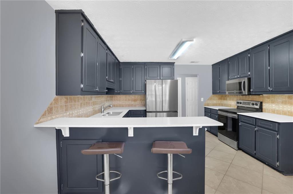 1805 Tribble Ridge Drive Lawrenceville, GA 30045 - Photo 16 of 46 a kitchen with stainless steel appliances a sink a stove a refrigerator cabinets and chairs