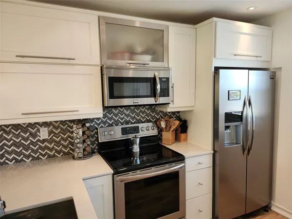 a kitchen with stainless steel appliances granite countertop a refrigerator and a stove top oven