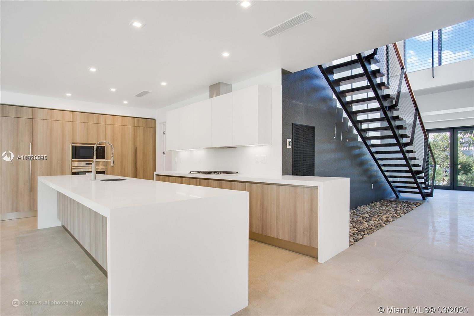 4530 Alton Road Miami Beach, FL 33140 - Photo 13 of 25 a large white kitchen with wooden floor and electronic appliances