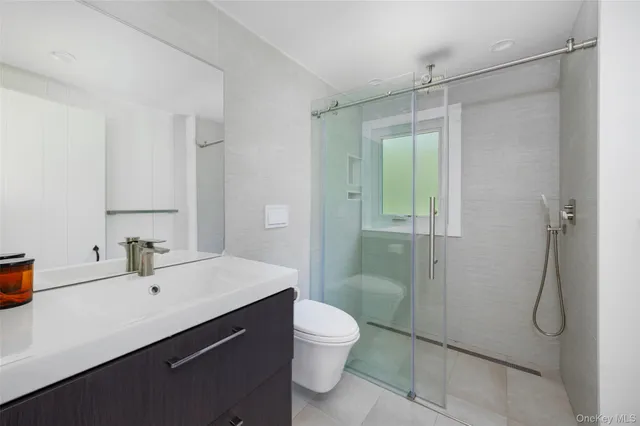 a bathroom with a shower sink vanity mirror and toilet