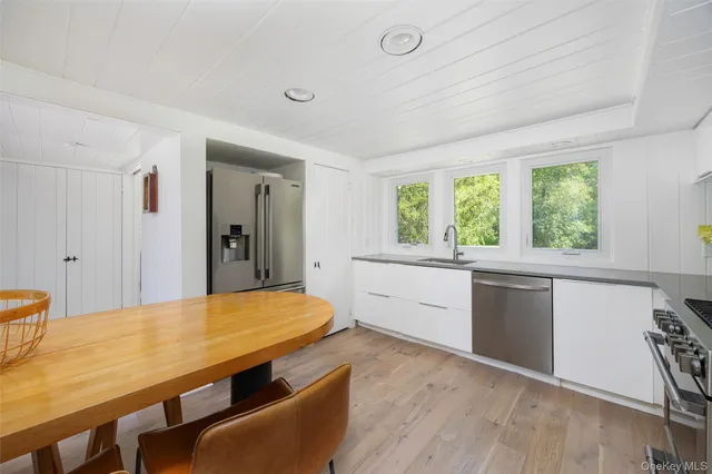 a kitchen with stainless steel appliances a kitchen island hardwood floor sink stove and wooden cabinets