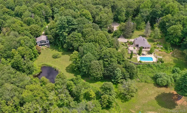 an aerial view of residential house with outdoor space and trees all around