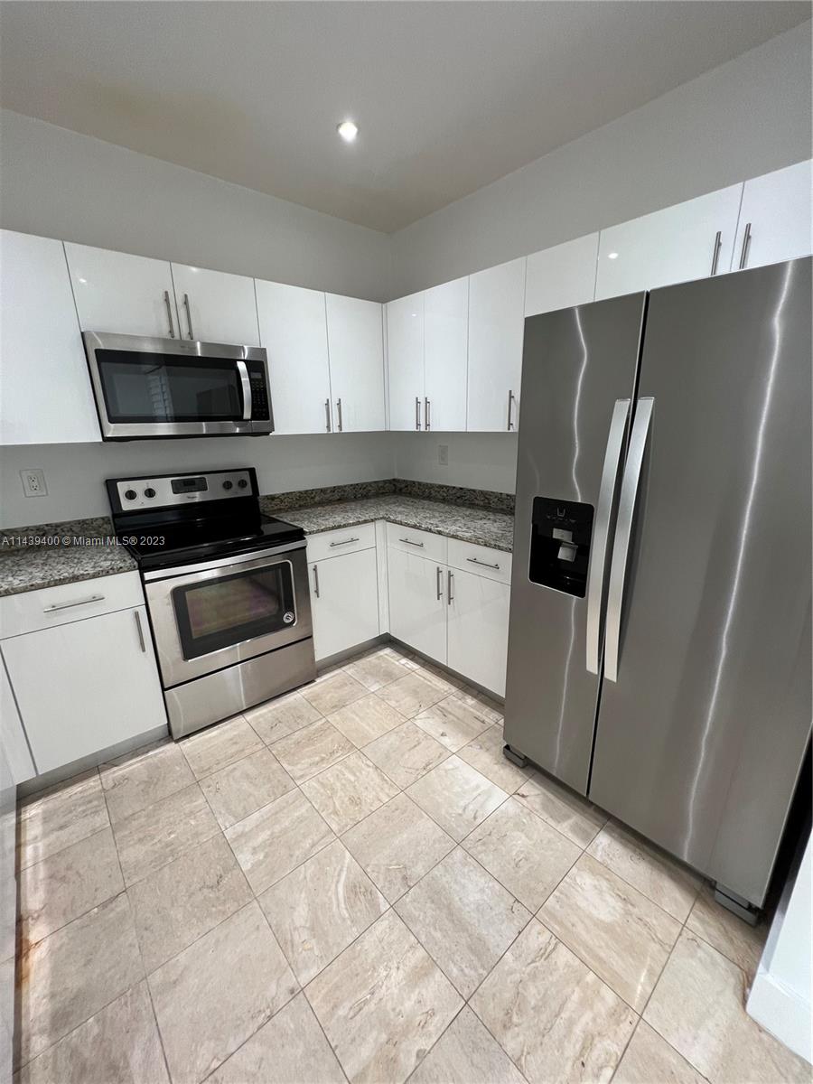 1915 Brickell Avenue, Unit TH16 Miami, FL 33129 - Photo 11 of 36 a kitchen with granite countertop a refrigerator and a stove top oven