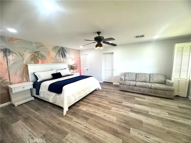 a spacious bedroom with a bed a couch and a ceiling fan