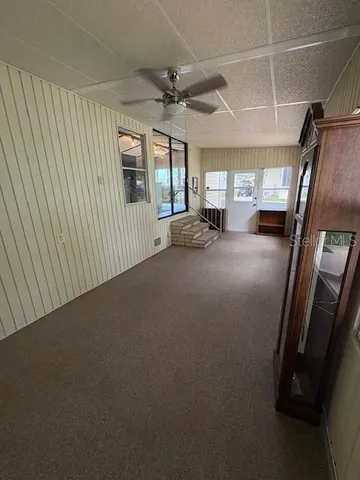 a view of a livingroom with furniture staircase ceiling fan and windows