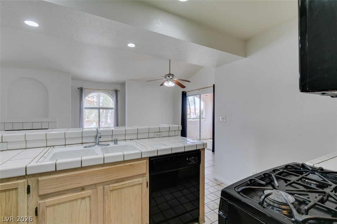 7570 West Flamingo Road, Unit 252 Las Vegas, NV 89147 - Photo 26 of 44 A functional kitchen provides a sink with tile countertops, a dishwasher, and a gas range.