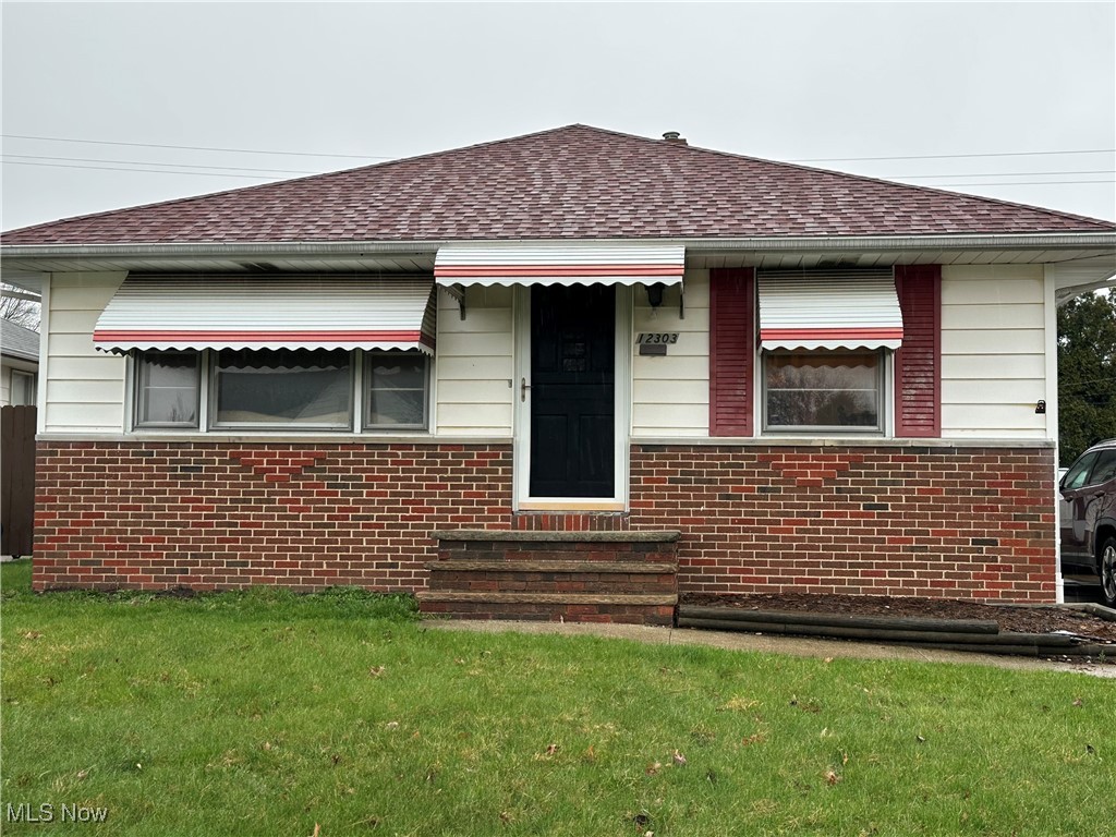 12303 Orme Road Garfield Heights, OH 44125 - Photo 1 of 22 Bungalow-style home featuring a front lawn, brick siding, and roof with shingles