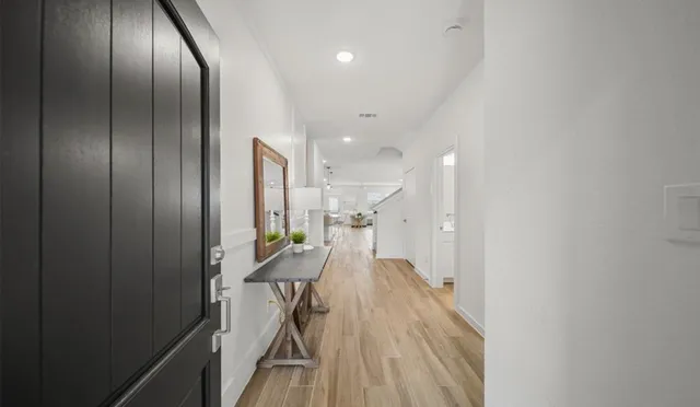 a view of a hallway with wooden floor stainless steel appliances