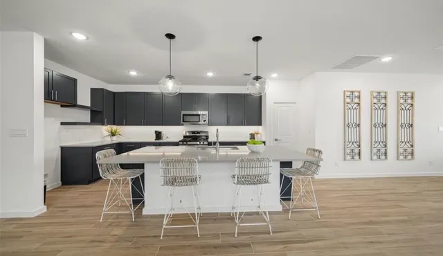 a kitchen with stainless steel appliances kitchen island granite countertop a dining table chairs and view living room