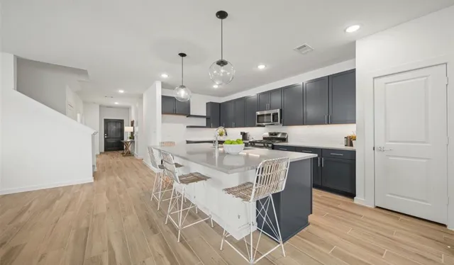 a kitchen with stainless steel appliances kitchen island granite countertop a wooden floor and a refrigerator