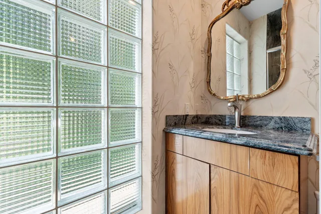 a bathroom with a granite countertop sink and large window