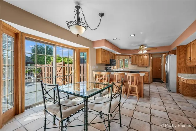 a kitchen with stainless steel appliances granite countertop a refrigerator a stove a sink a dining table and chairs with wooden floor