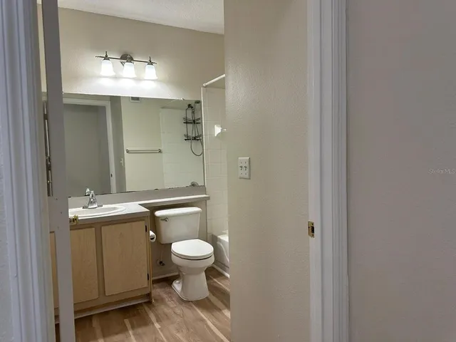 a bathroom with a granite countertop toilet a mirror and a shower
