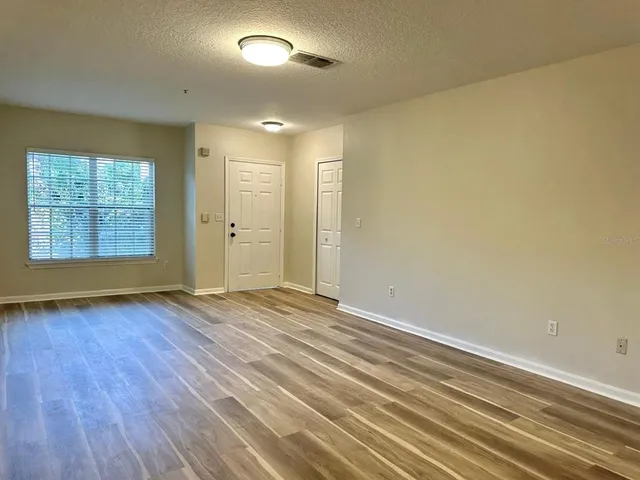 an empty room with wooden floor and windows