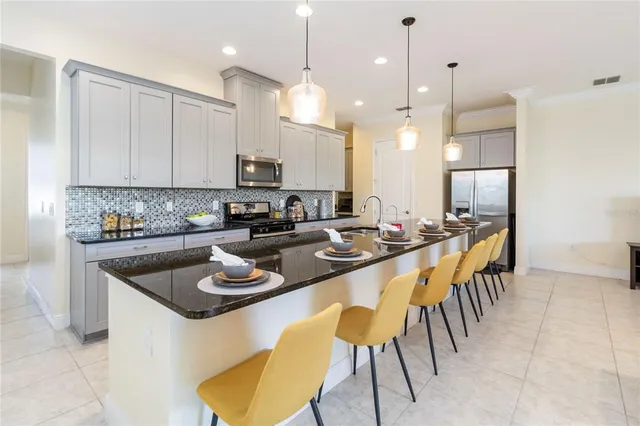 a kitchen with stainless steel appliances granite countertop a sink a stove a refrigerator a microwave oven a dining table and chairs