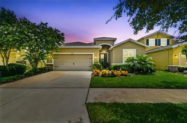 a front view of a house with a garden and trees