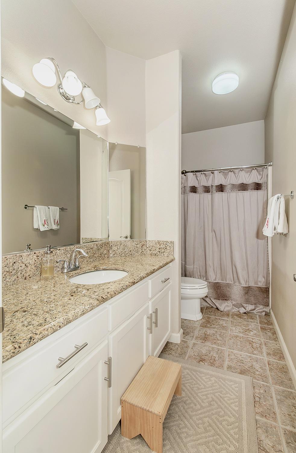 2074 East Revere Road Fresno, CA 93720 - Photo 22 of 39 a bathroom with a granite countertop sink a toilet and a mirror
