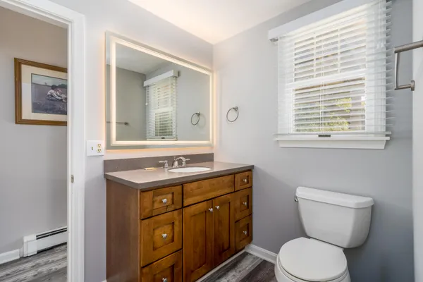 a bathroom with a toilet a sink a mirror and a window