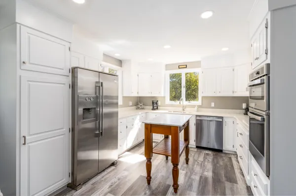a kitchen with stainless steel appliances granite countertop a refrigerator and a stove top oven