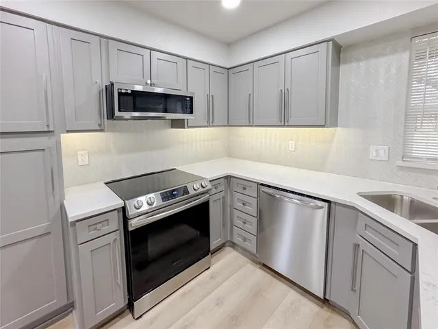 a kitchen with granite countertop white cabinets stainless steel appliances and sink