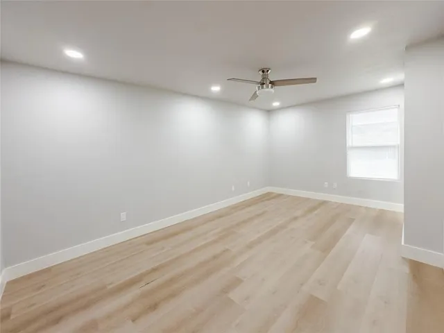 an empty room with a window and ceiling fan