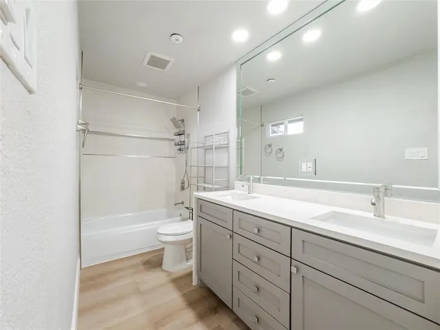 a bathroom with a double vanity sink toilet mirror and shower