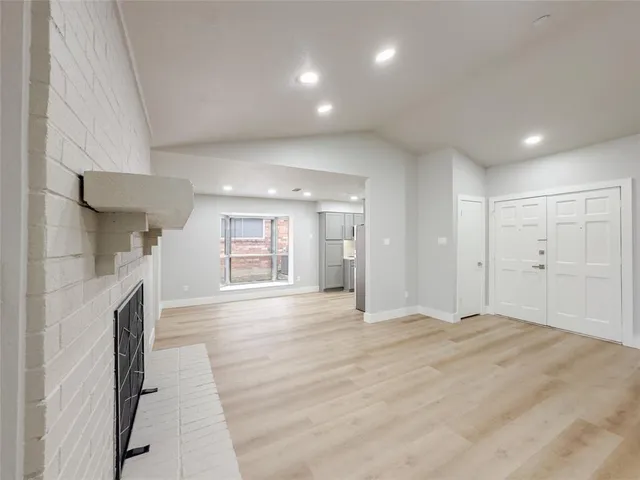 a view of empty room with wooden floor and fireplace