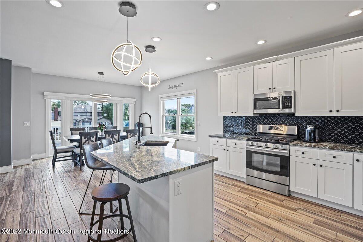 35 Channel Road Toms River, NJ 08753 - Photo 10 of 41 a kitchen with stainless steel appliances granite countertop a stove a sink dishwasher a dining table and chairs with wooden floor