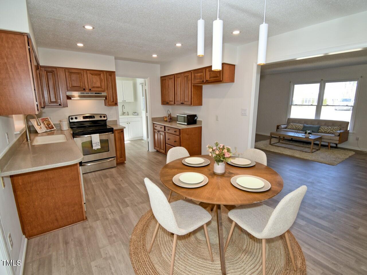 3217 Banks Road Raleigh, NC 27603 - Photo 7 of 29 a kitchen with stainless steel appliances granite countertop a stove top oven a dining table and chairs with wooden floor