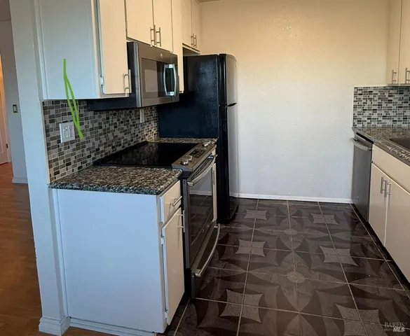 a kitchen with granite countertop a sink stove and cabinets