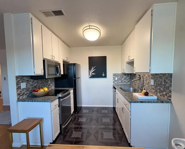 a kitchen with stainless steel appliances granite countertop a sink and a stove top oven