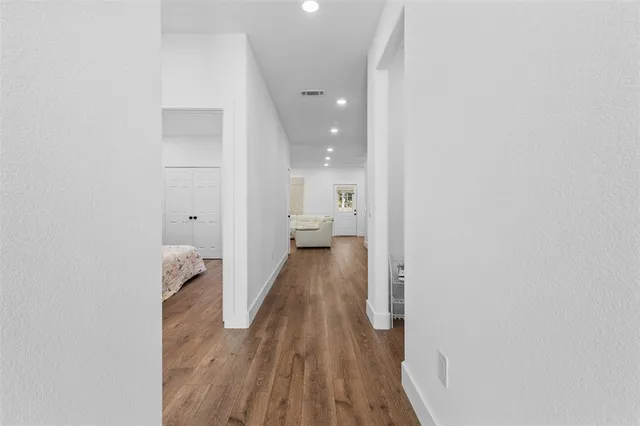 a view of a hallway with wooden floor and a bathroom