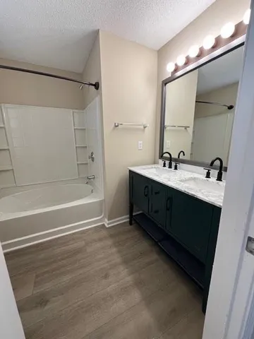 a bathroom with a double vanity sink a mirror and a bathtub