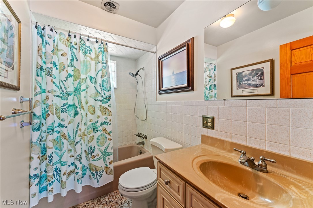 3612 Ridge Road Cortland, OH 44410 - Photo 16 of 36 Bathroom with tile walls, vanity, and shower / bath combination with curtain