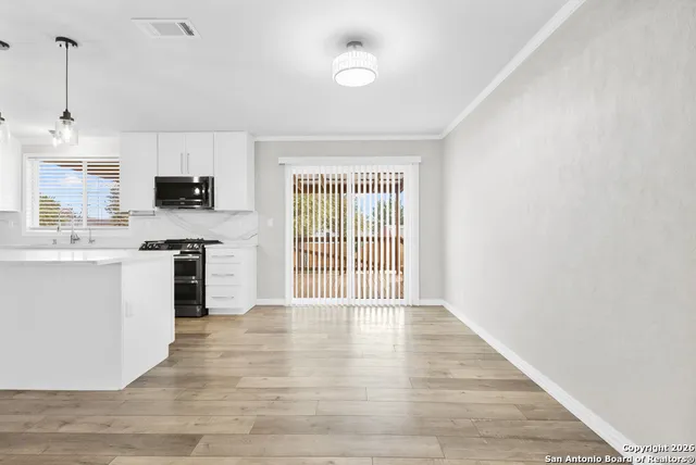 a large kitchen with granite countertop a stove top oven a sink dishwasher and a refrigerator with wooden floor