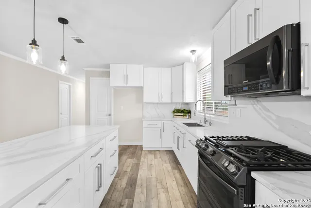 a kitchen with stainless steel appliances a sink a stove a microwave and cabinets