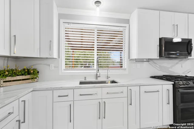 a kitchen with stainless steel appliances white cabinets and a window