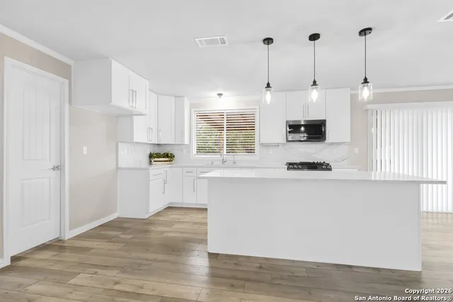 a kitchen with kitchen island white cabinets and white appliances