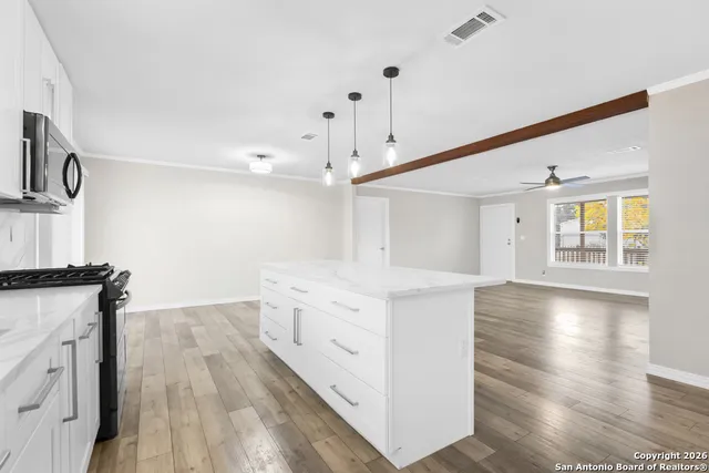 a view of a kitchen with stainless steel appliances granite countertop a stove and a wooden floors
