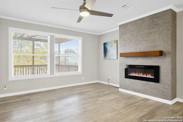 a view of an empty room with wooden floor a fireplace and a window