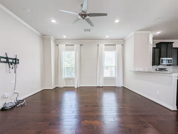 a view of an empty room with a window and wooden floor