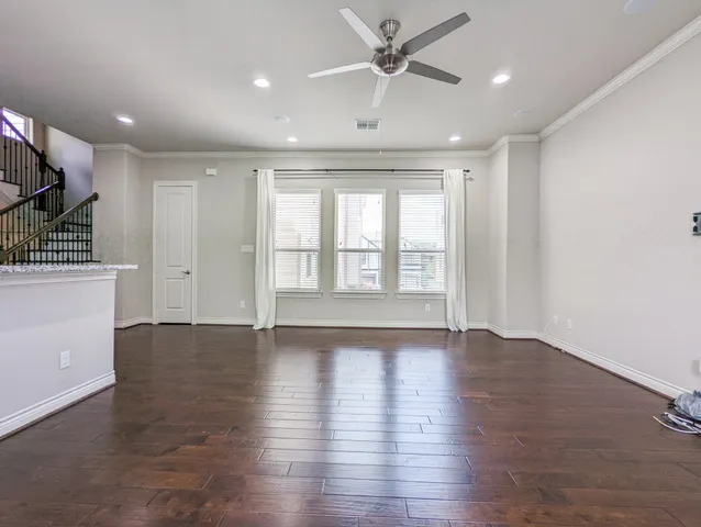 a view of an empty room with window and wooden floor