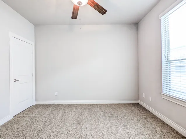 an empty room with a window and a fan