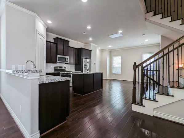 a kitchen with stainless steel appliances granite countertop a refrigerator a sink dishwasher a stove and a microwave oven on the wooden floor
