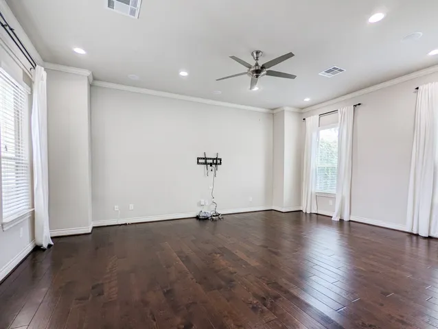 an empty room with wooden floor a ceiling fan and windows