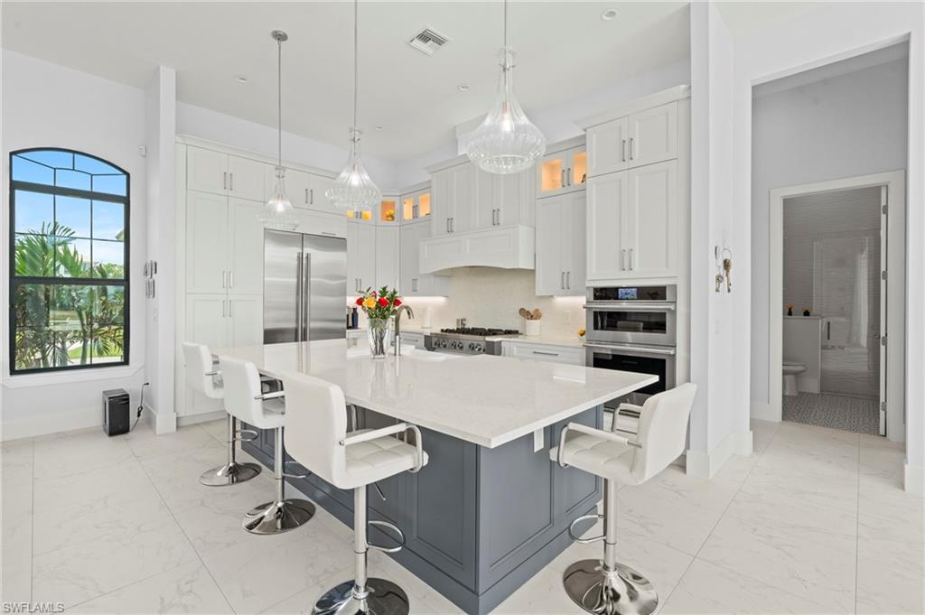 388 Pine Avenue Naples, FL 34108 - Photo 11 of 42 a kitchen with kitchen island a stove a table and chairs in it
