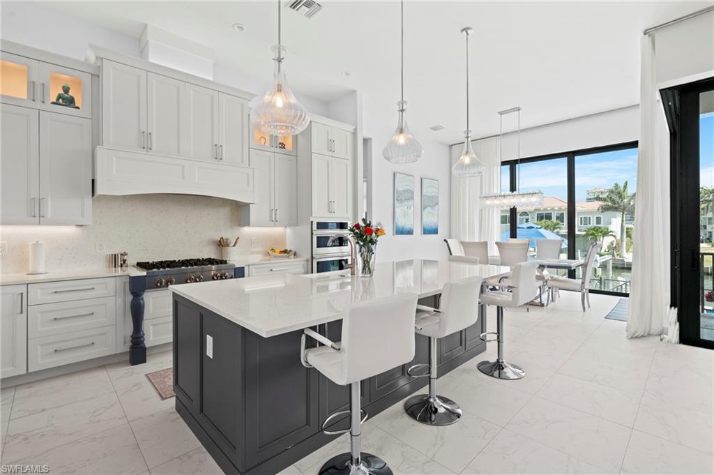 388 Pine Avenue Naples, FL 34108 - Photo 12 of 42 a large kitchen with kitchen island a large counter top space a sink stainless steel appliances and cabinets