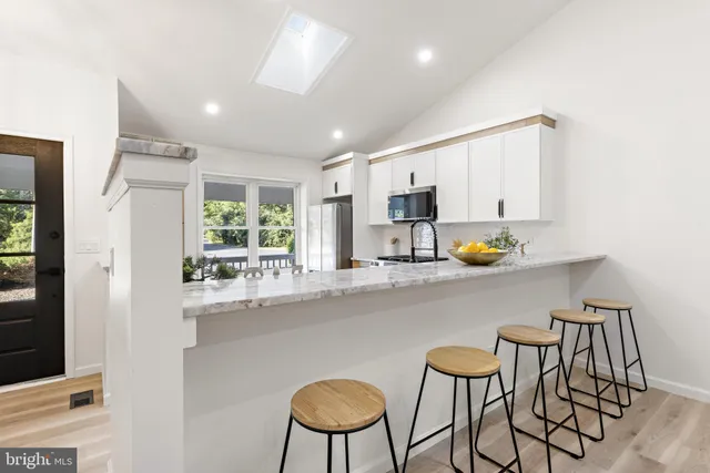 a kitchen with stainless steel appliances a dining table chairs and window
