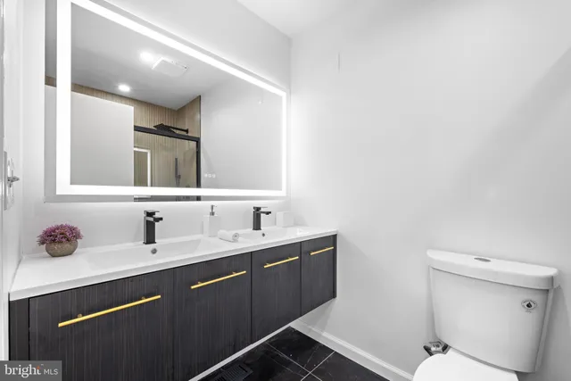 a bathroom with a toilet sink double vanity and mirror